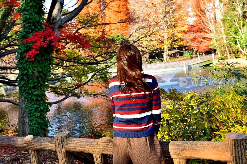 年轻的日本女人在猪城公园放松/享受秋天的颜色